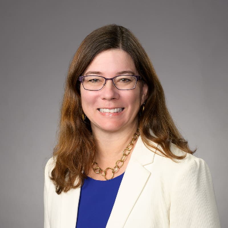 A woman wearing glasses and a white jacket