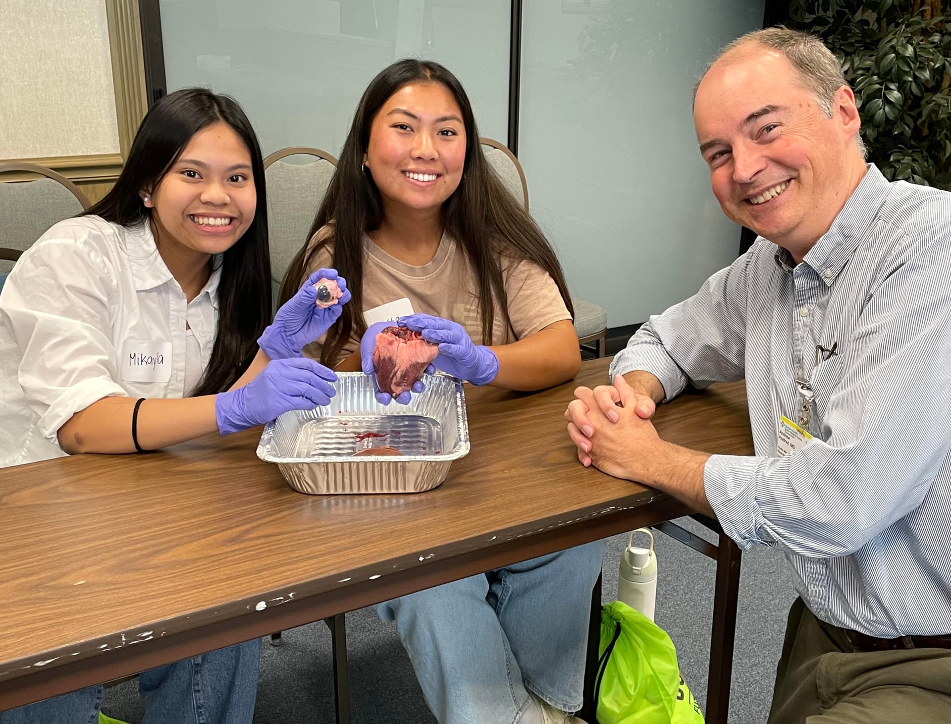 Three people sitting at a table with gloves on