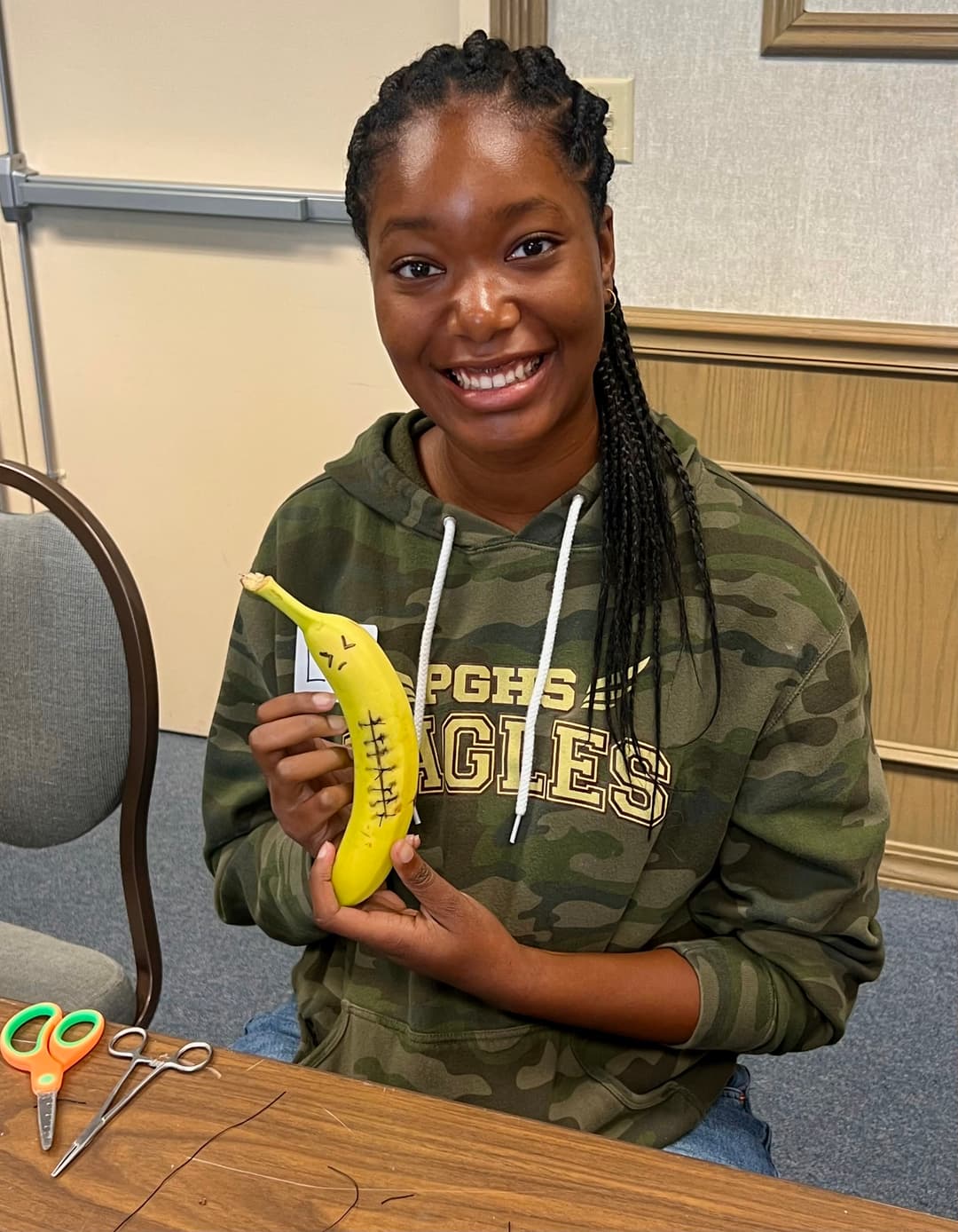A woman sitting at a table holding a banana