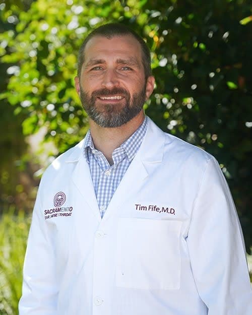 A man with a beard wearing a white lab coat