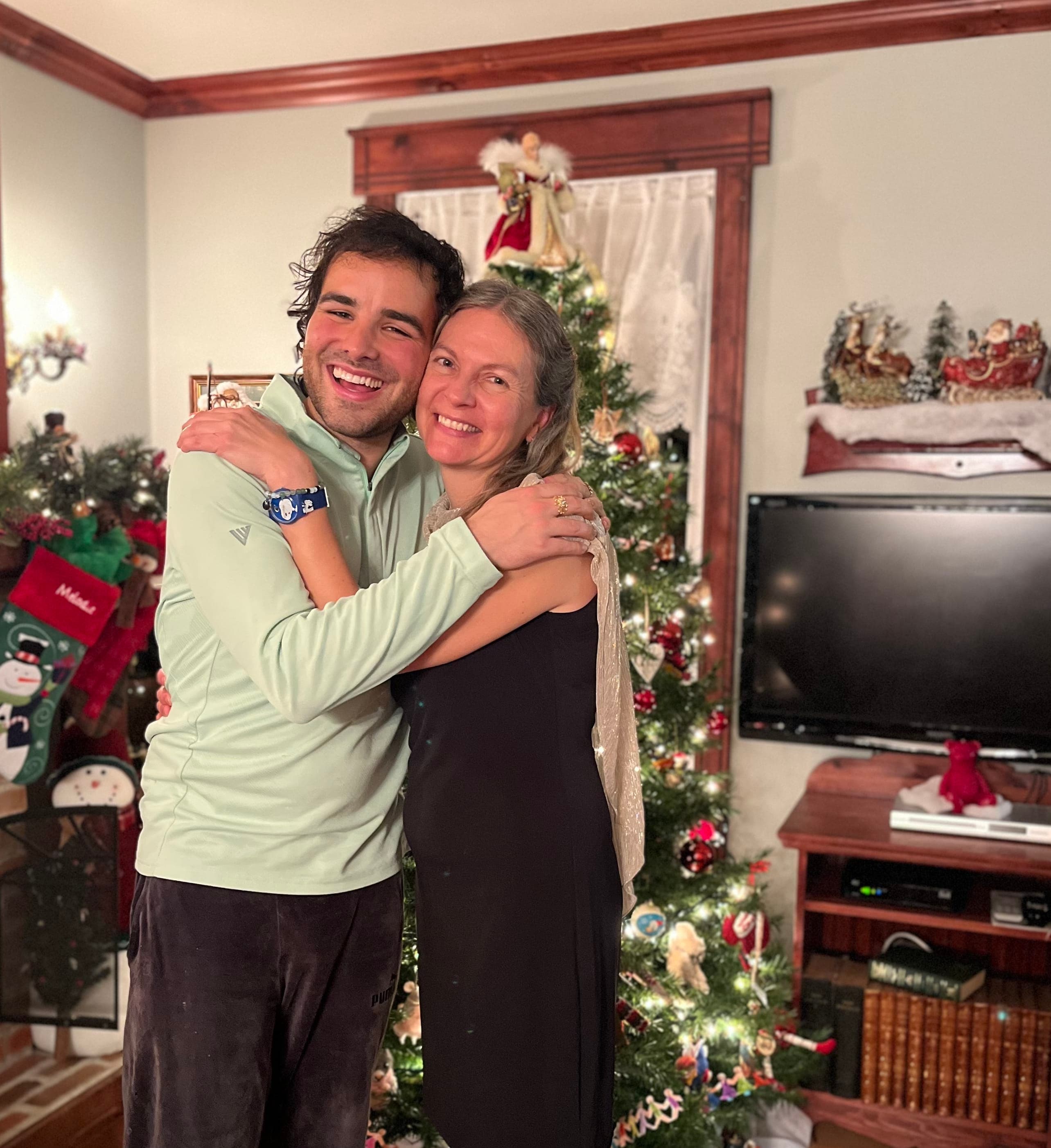 A man and woman hugging in front of a christmas tree