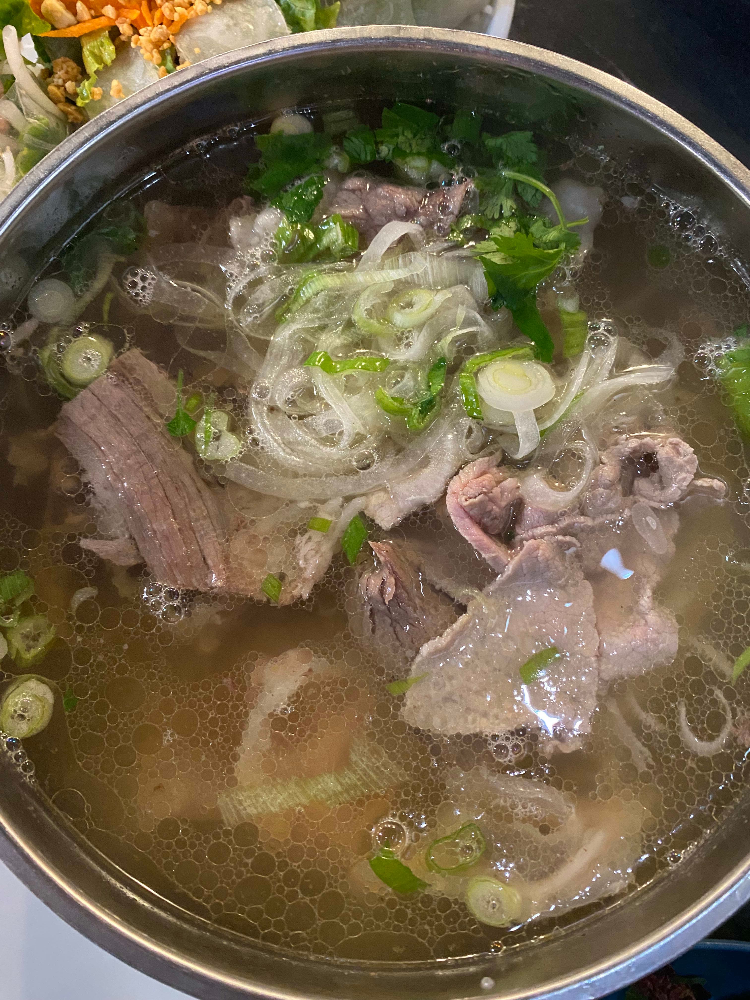 A pot of soup with meat, onions and broccoli