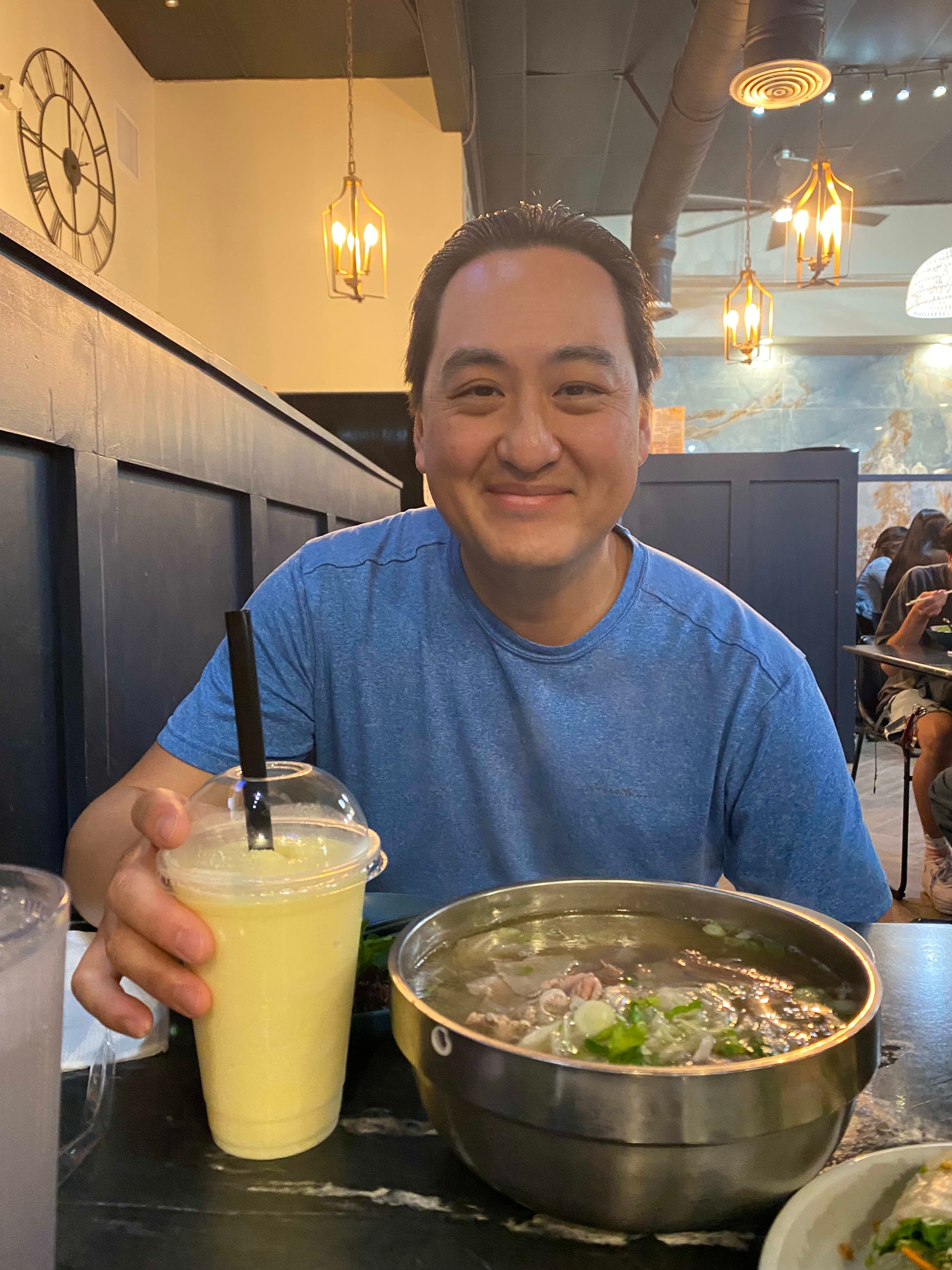 A man sitting at a table with a bowl of food and a drink