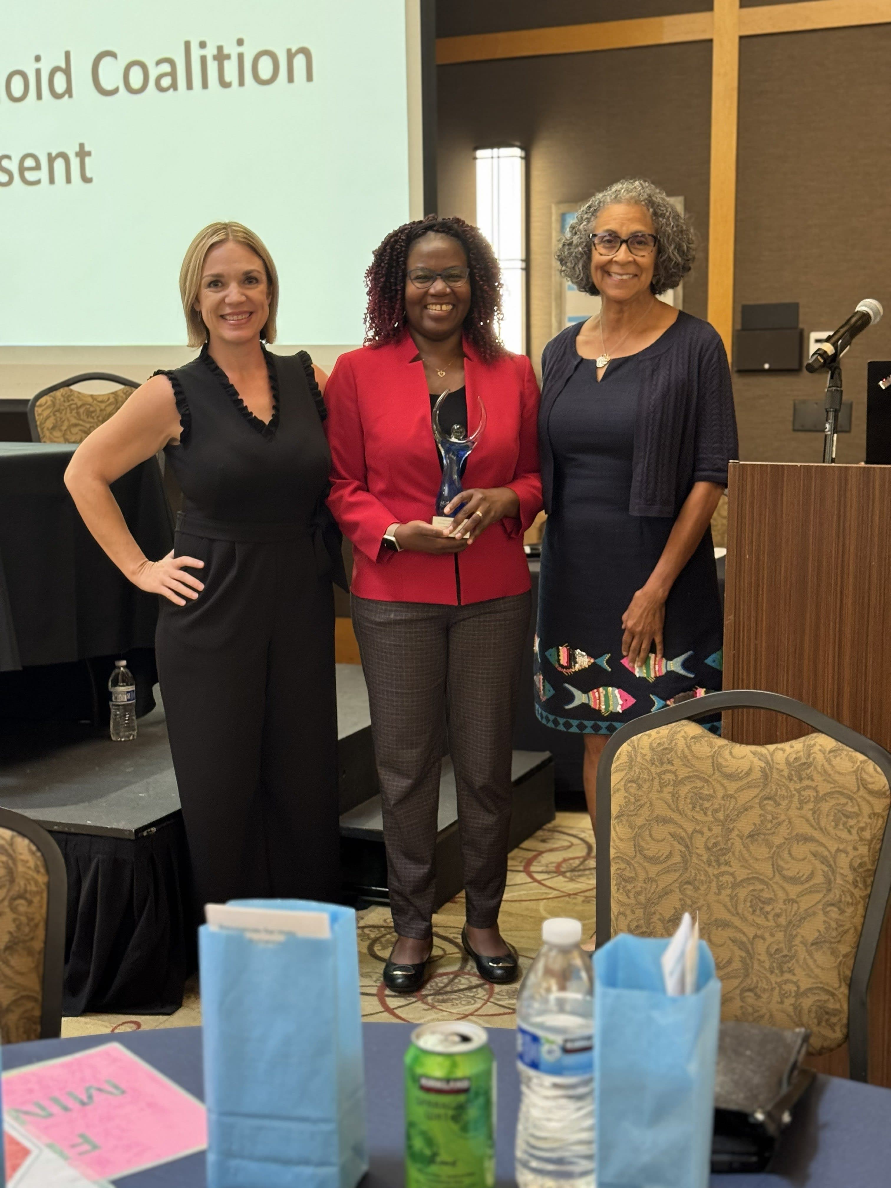 Three women standing next to each other in front of a projector screen
