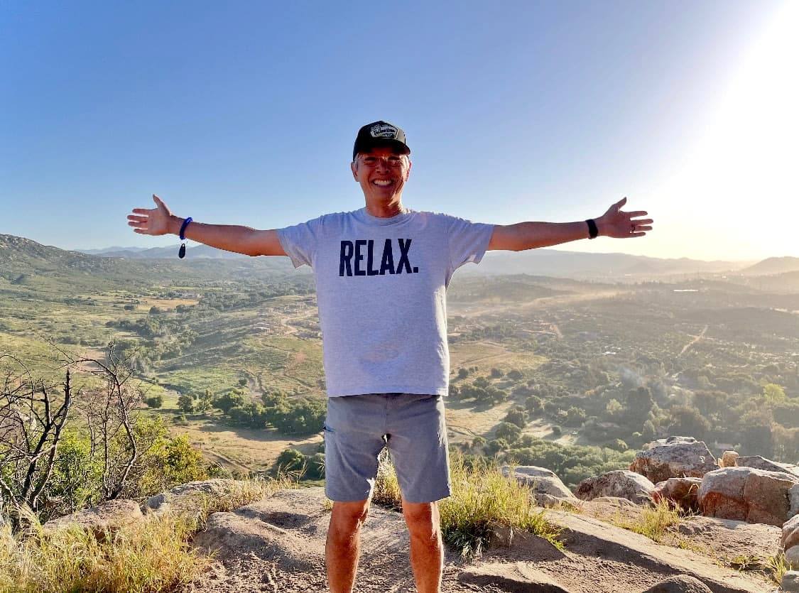 A man standing on top of a mountain with his arms outstretched